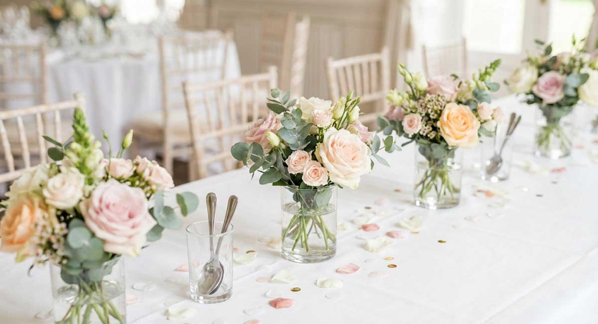 Elegant gedeckter Hochzeitstisch mit Blumen in Pastellfarben und dezent gestreutem Konfetti